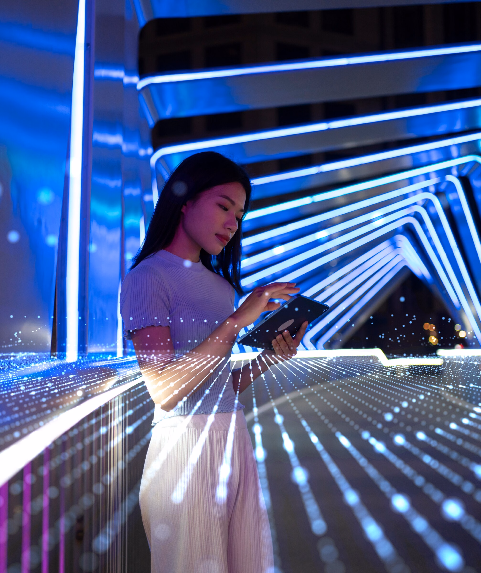 Visitor interacting with a tablet inside an illuminated digital installation